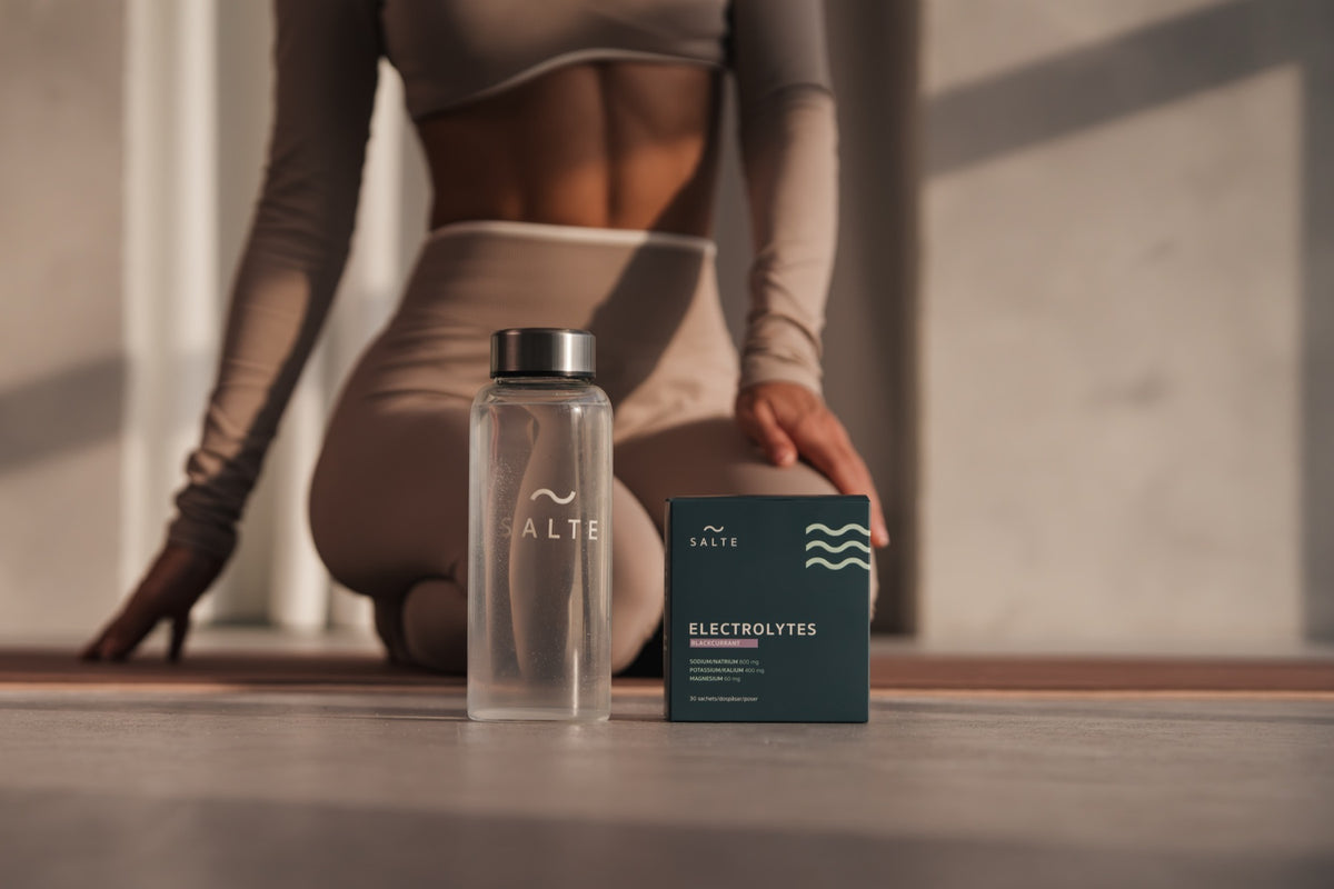 SALTE box and glass bottle on a yoga mat in morning light
