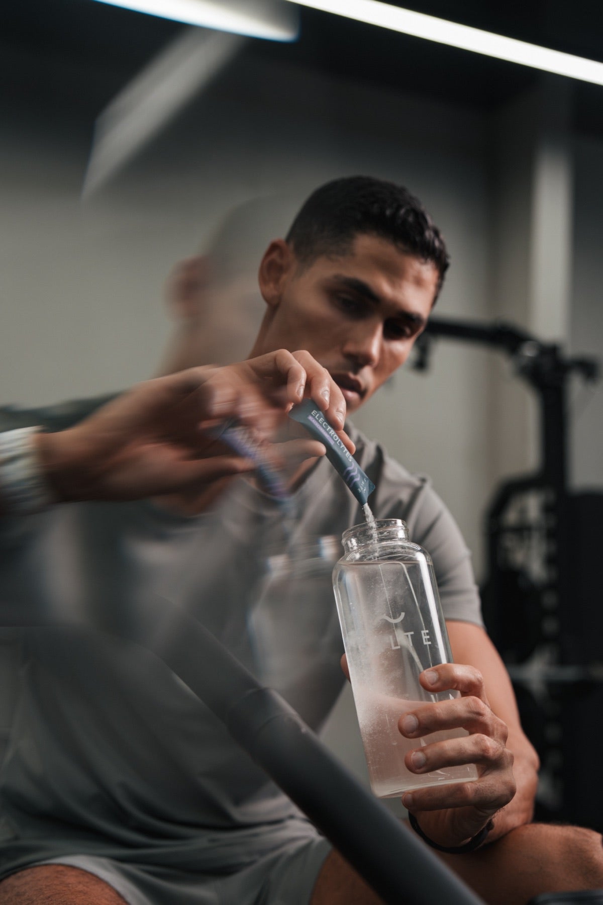 Man pouring a SALTE sachet into a water bottle in the gym