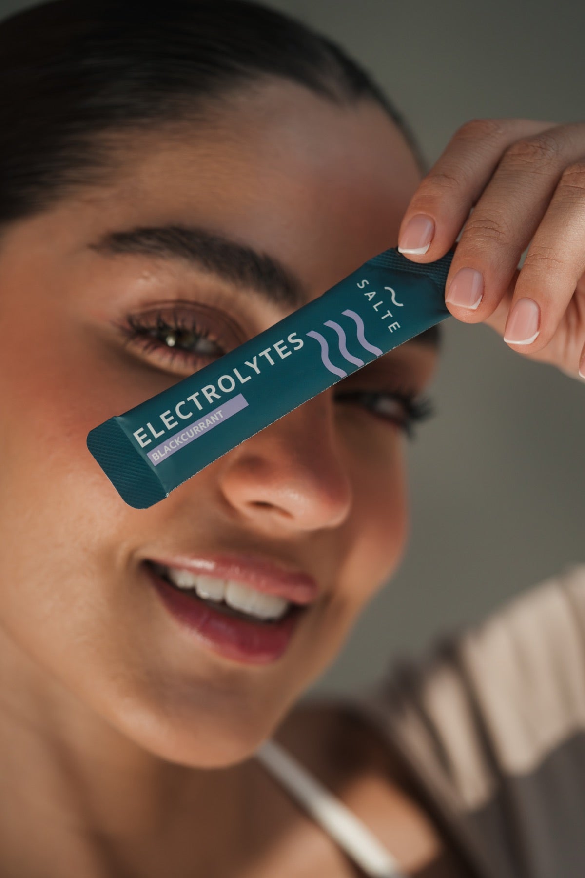Smiling person holding a SALTE sachet